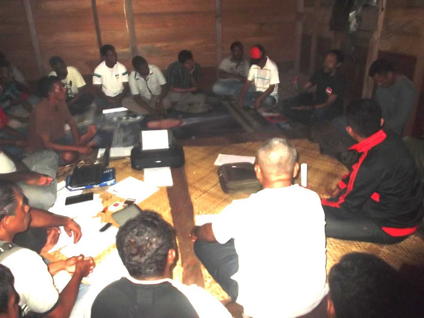 Rudi, right, sits with local activists at the ‘Hyacinth Post’ in Dobo in 2013.