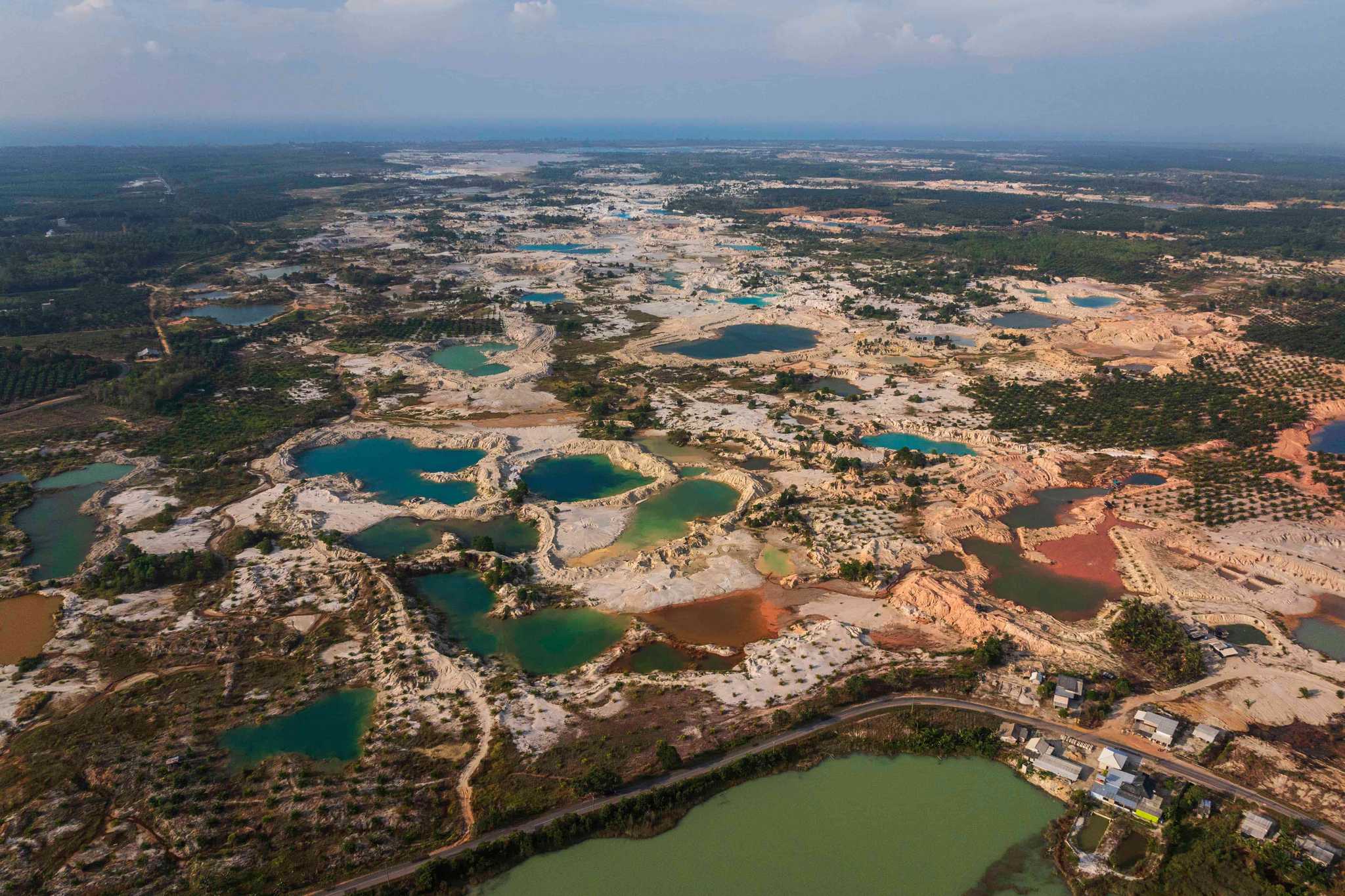 Green and blue mining pits scare a landscape.