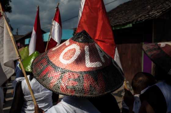 Villagers take part in the rice cake festival in 2019. The traditional hat is emblazoned with the words ‘Tolak Pabrik Semen’: Reject the cement factory. By Leo Plunkett for The Gecko Project/Mongabay.